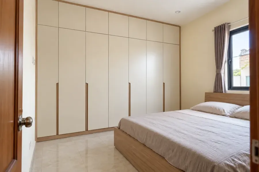 Hệ tủ quần áo cánh mở màu trắng ngà kết hợp vân gỗ được bố trí theo diện tích phòng ngủ thực tế