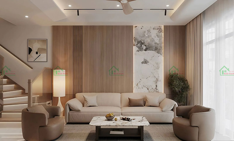 Vách tường ốp gỗ và đá marble tạo điểm nhấn ấn tượng cho phòng khách, kết hợp hài hòa với nội thất màu kem và nâu đất.