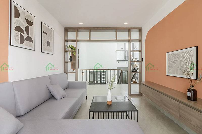 Thiết kế hiện đại cho khu vực sinh hoạt chung tầng lửng, với sofa màu xám, bàn trà kim loại và vách ngăn gỗ tạo không gian mở