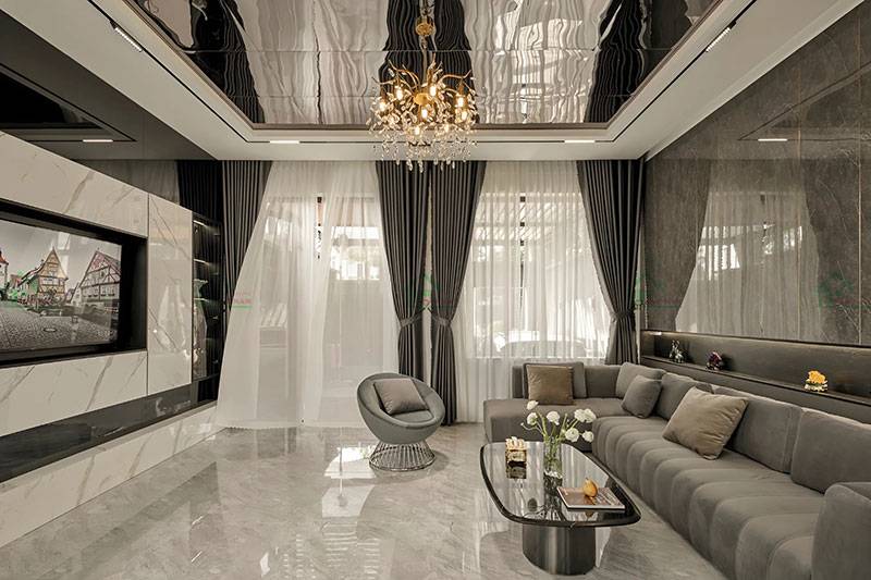 Tường ốp đá cẩm thạch sáng màu tạo nên vẻ đẹp sang trọng, kết hợp với sofa màu xám nhạt và hệ thống đèn chiếu sáng hiện đại.