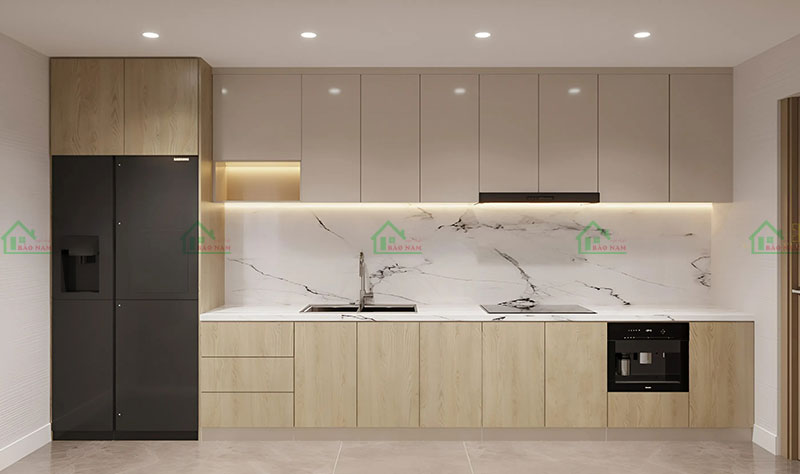 Tủ bếp vân gỗ sồi tự nhiên và màu kem nhạt, mặt bếp ốp đá cẩm thạch trắng, tạo không gian bếp sang trọng và ấm cúng.