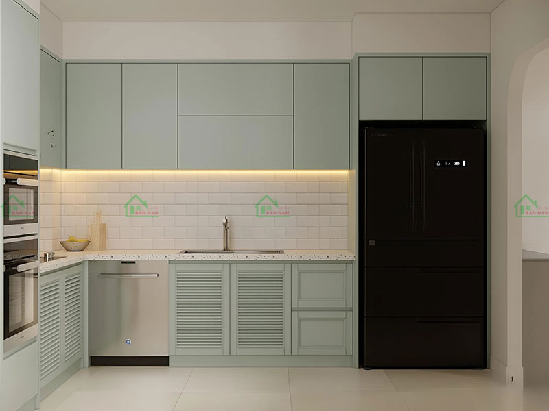 Tủ bếp góc chữ L màu xanh mint, với mặt bếp màu sáng và gạch ốp tường màu trắng