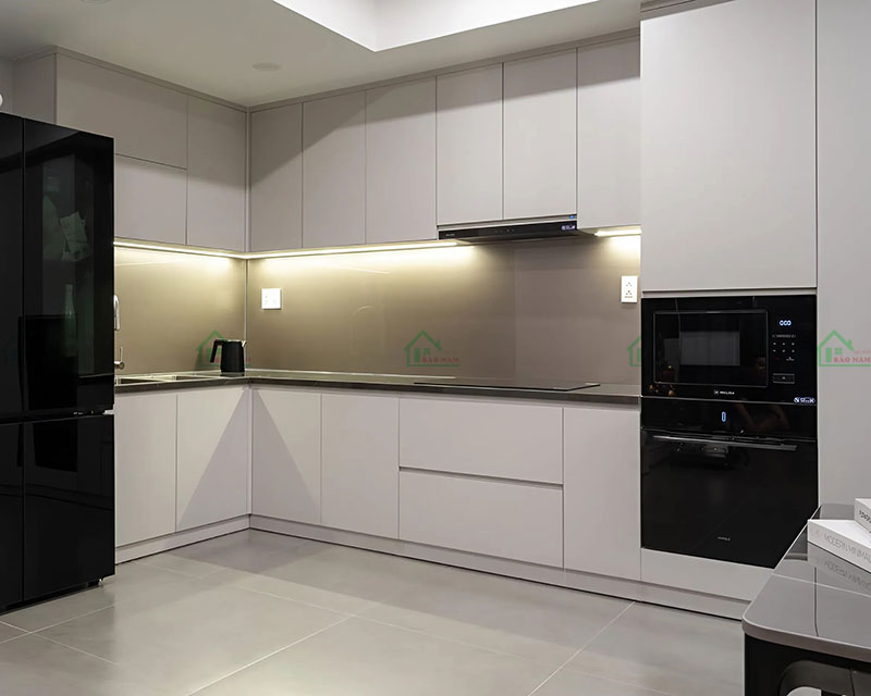 Tủ bếp chữ L màu trắng tối giản, kết hợp với mặt bếp và thiết bị màu đen tạo điểm nhấn mạnh mẽ. Tủ bếp chữ L màu trắng tối giản, kết hợp với mặt bếp và thiết bị màu đen tạo điểm nhấn mạnh mẽ.